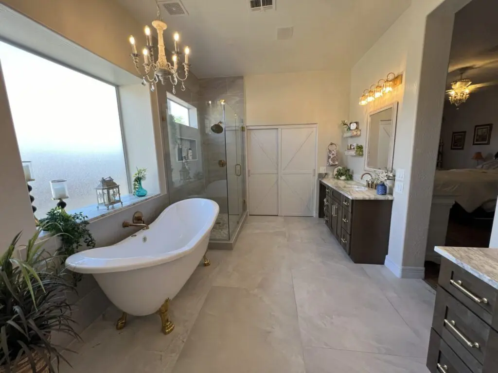 Luxurious master bathroom with freestanding soaking tub, walk-in shower, dual vanity with marble countertop, dark cabinetry, and elegant chandelier lighting