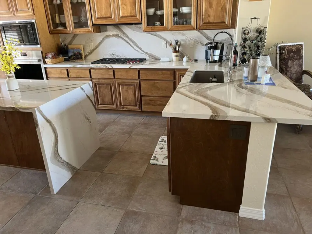 Modern kitchen with marble countertops, wood cabinetry, and dual islands with white waterfall edges