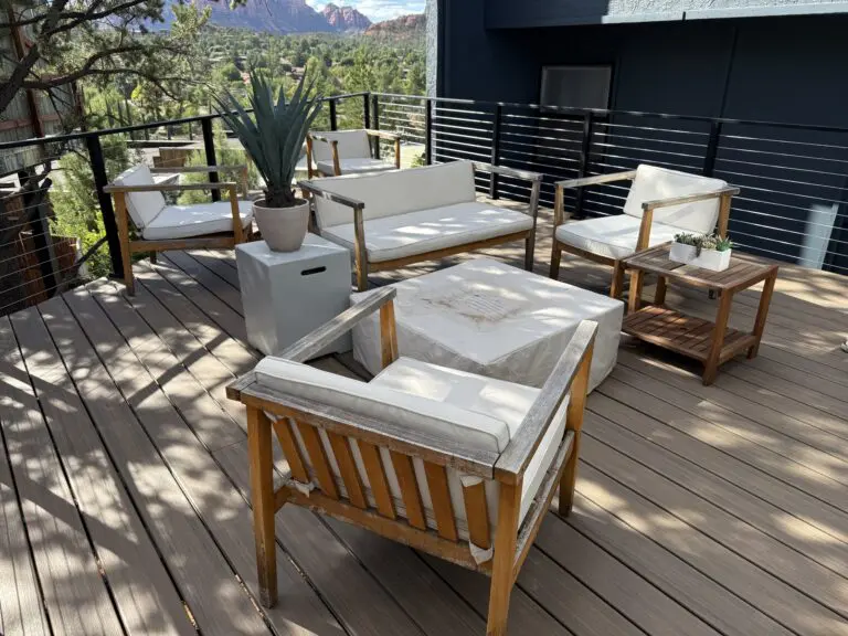 Modern rooftop patio with wooden furniture, white cushions, fire pit, and mountain views in background