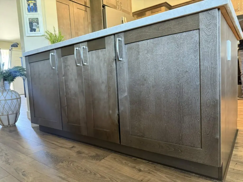 Modern kitchen island with dark wood cabinetry and stainless steel countertop in a bright, open-concept home interior