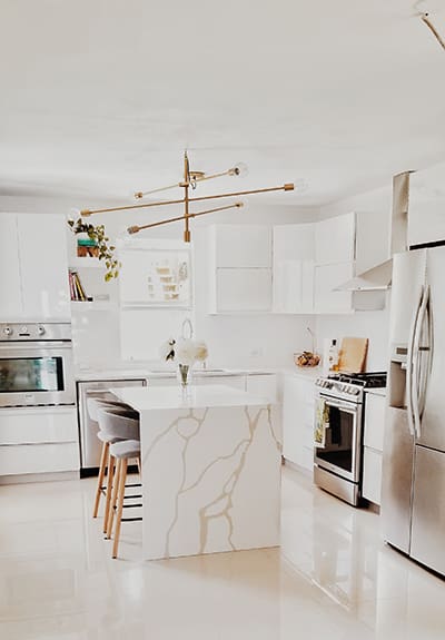 A kitchen with white cabinets and marble counter tops.