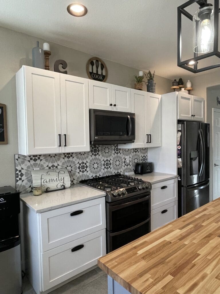 A kitchen with white cabinets and black appliances.