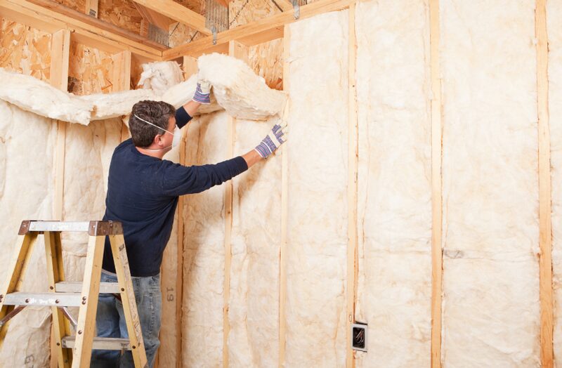 A worker installs insulation in the walls of a new home addon, a crucial step in the home renovation process.