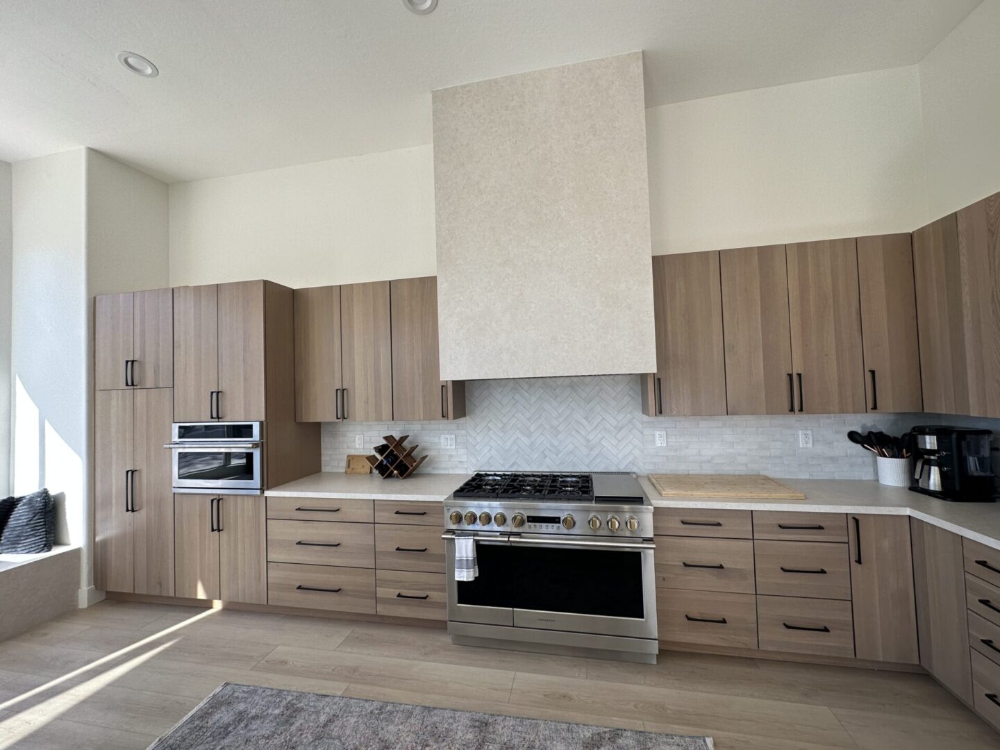 Modern kitchen with wood cabinetry, stainless steel gas range, white subway tile backsplash, and light wood flooring