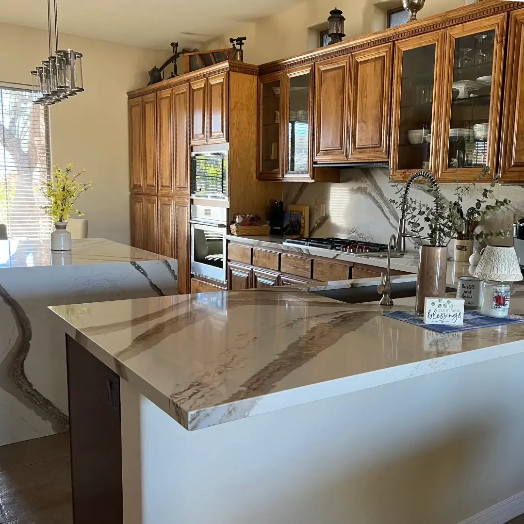 Elegant kitchen with marble-topped island, wood cabinetry, stainless steel appliances, and pendant lighting overlooking dining area