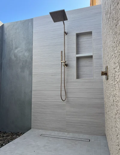 Modern custom outdoor shower with rainfall showerhead, handheld sprayer, tiled walls, and linear drain