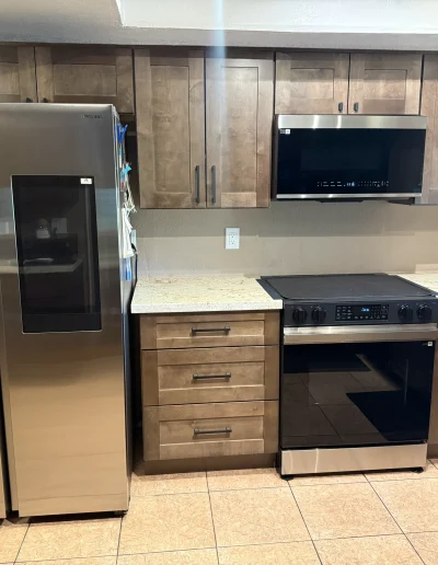 Remodeled kitchen with wood shaker cabinets, light stone countertops, stainless steel appliances, and modern black cabinet hardware