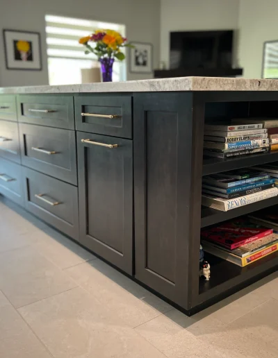 Custom dark wood kitchen island with stone countertop, built-in drawers, cabinets, open shelving, and brass hardware