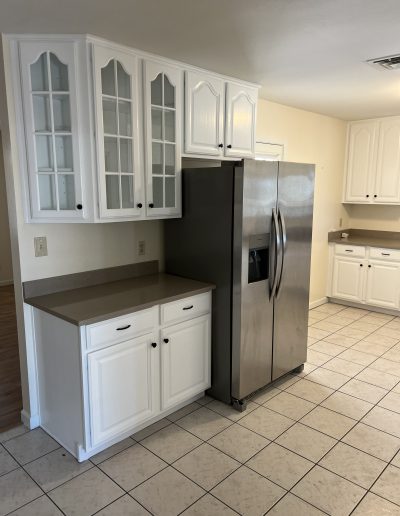 Updated kitchen with painted white cabinets, dark countertops, black hardware, and stainless steel refrigerator