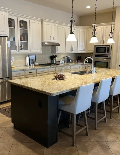 Remodeled kitchen with white painted cabinets, granite countertops, tile backsplash, stainless steel appliances, and large center island