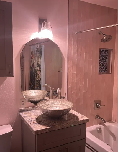 Remodeled bathroom with vessel sink, granite countertop, tiled tub and shower surround, built-in shower niche, and brushed nickel fixtures