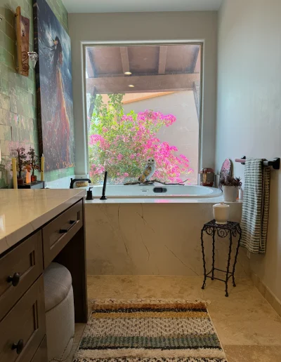 Remodeled primary bathroom with built-in soaking tub, stone surround, custom vanity, and large picture window