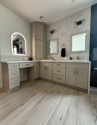 Custom master bathroom vanity with dual sinks, makeup station, taupe cabinetry, decorative tile backsplash, and wood-look flooring