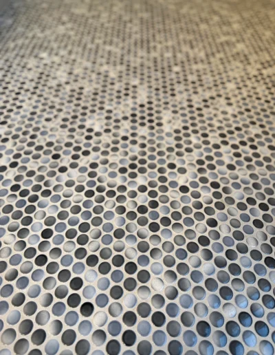 Close-up of gray and white penny tile shower flooring installed as part of a primary bathroom remodel