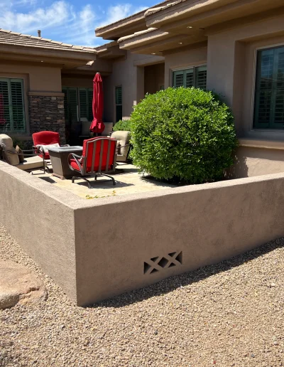 Remodeled outdoor patio with stucco pony wall, seating area, desert landscaping, and stone accents