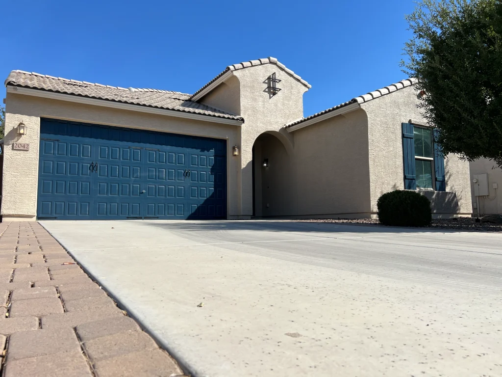 Arizona stucco home exterior repaint with deep blue garage door and matching window shutters, beige stucco, and tiled roof
