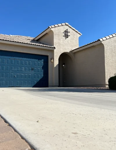 Arizona stucco home exterior repaint with deep blue garage door and matching window shutters, beige stucco, and tiled roof
