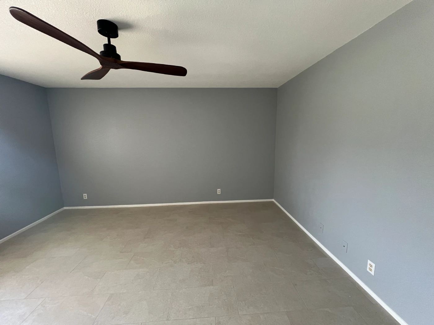 garage conversion Garage conversion interior featuring gray painted walls, modern tile flooring, white baseboards, and a contemporary ceiling fan