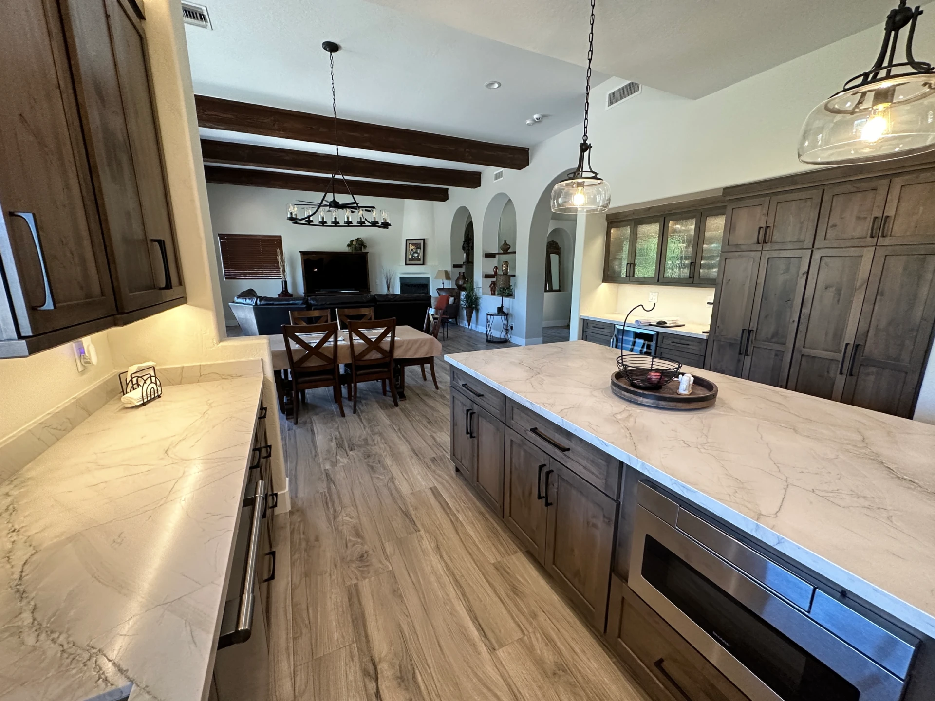 wholehome-slider4 Modern kitchen remodel featuring a large quartz countertop island, custom wood cabinetry, stainless steel appliances, and an open-concept living area